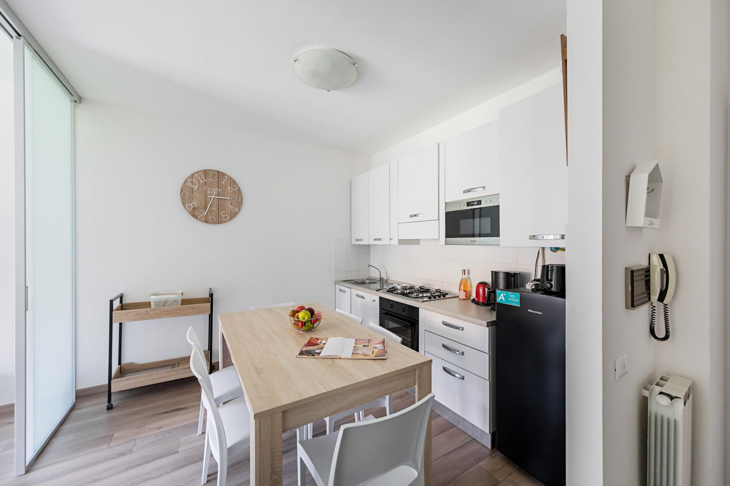 Una cocina moderna con armarios blancos, una mesa de comedor de madera y un frutero.