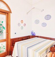 Una habitación con puerta de madera, una cama con colcha a rayas y decoración en las paredes que incluye platos y una lámpara colgante.