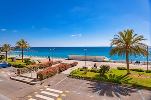 Un paseo marítimo con vistas despejadas al mar, palmeras y un sendero para peatones.