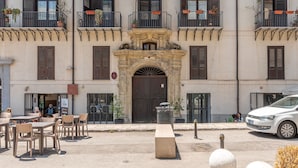 A building with multiple balconies, some with plants. There are outdoor tables and chairs. - Cala Loft by Wonderful Italy (Palermo)