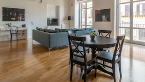 A spacious living area with a wooden ceiling, a sofa, a dining table with chairs, and a TV. - Cala Loft by Wonderful Italy (Palermo)