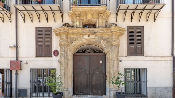 A historic building with a large wooden double door, flanked by two potted plants. - Cala Loft by Wonderful Italy (Palermo)