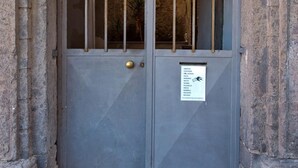 A closed metal door with a sign listing room names. - Casa Mil by Wonderful Italy (Naples)