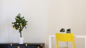 A small table with a potted plant and a yellow chair. - Casa Mil by Wonderful Italy (Naples)