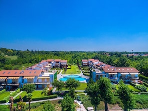 A residential complex with multiple buildings, a central swimming pool, and well-maintained gardens.
