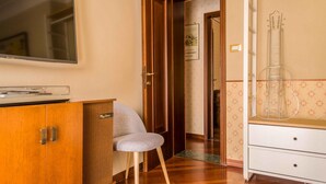 A room with a wooden cabinet, a television, a chair, and a white dresser with drawers. - Fossalta Vintage Apartment by Wonderful Italy (Bologna)