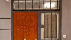 Uma porta de madeira com um emblema circular, um portão de metal com desenhos circulares e um parapeito de pedra.