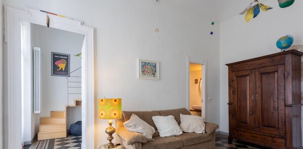 Een woonkamer met een bank, een lamp, een houten kast en een wereldbol bovenop de kast.