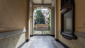 Um corredor com piso de azulejos que leva a um portão com detalhe em ferro ornamental.