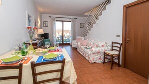 Un coin repas avec une table dressée pour deux personnes, un canapé et un escalier menant à l’étage supérieur.