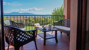 Un balcon avec des fauteuils en osier, une table avec un service à thé et une vue sur les montagnes.