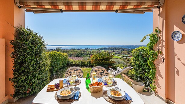 An outdoor dining area with a table set for two, overlooking a scenic landscape. - Residence Giardino 3 by Wonderful Italy (Soiano del Lago)