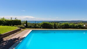 A clear blue swimming pool with a view of a distant landscape and a body of water. - Residence Giardino 3 by Wonderful Italy (Soiano del Lago)