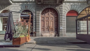 A building facade with a large wooden door, a sign reading "Alimentari," and a small outdoor seating area with a plant. - A Due Passi Dalla Mole by Wonderful Italy (Turin)