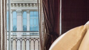 A room with a view of a building through a window with ornate metal railings and curtains. - A Due Passi Dalla Mole by Wonderful Italy (Turin)