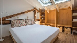 A bedroom with a sloped ceiling, skylights, a bed, wooden shelving, and baskets. - Le Niche Holiday Home - Terrace by Wonderful Italy (Palermo)