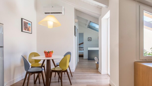 A modern kitchen with a dining area, wooden flooring, and a hanging light fixture. - Le Niche Holiday Home - Terrace by Wonderful Italy (Palermo)