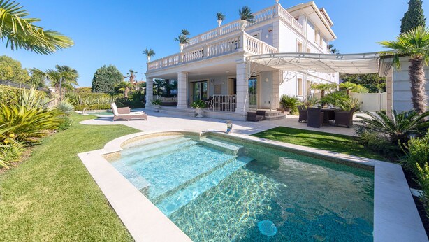 Una casa grande de dos pisos con piscina en el jardín delantero.