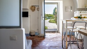 A kitchen with a view to the outside, a dining area with metal chairs, and a small stool. - Loft Sole by Wonderful Italy (Giarre)