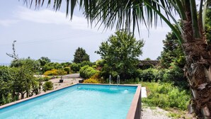 A rectangular swimming pool with a clear blue water surface, surrounded by lush greenery and trees. - Loft Sole by Wonderful Italy (Giarre)