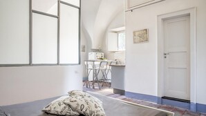 A room with a bed, a dining area, and a kitchen in the background. - Loft Sole by Wonderful Italy (Giarre)
