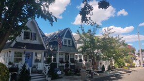 A two-story house with a porch, a flag, and a mailbox.