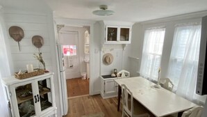A compact kitchen with white cabinetry, a central island, and a dining area with a table and chairs. - Charming Beach Cottage,  Newly renovated. located in Ocean City Nj. (Ocean City)