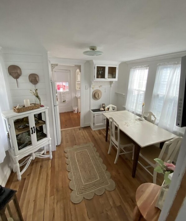 A compact kitchen with white cabinetry, a central island, and a dining area with a table and chairs. - Charming Beach Cottage,  Newly renovated. located in Ocean City Nj. (Ocean City)