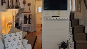 A cozy living room with a fireplace, a television mounted on the wall, and a staircase leading to another level. - Charming Beach Cottage,  Newly renovated. located in Ocean City Nj. (Ocean City)