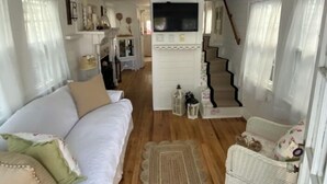 A spacious living room with a sofa, a wicker chair, a staircase, and a TV. - Charming Beach Cottage,  Newly renovated. located in Ocean City Nj. (Ocean City)
