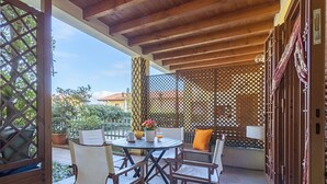 An outdoor patio with a wooden ceiling, a table with chairs, and a decorative fence. - Alessandra 2 Apartment by Wonderful Italy (Padenghe sul Garda)