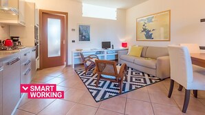 A modern apartment with a kitchen, a dining area, and a living room. There is a map on the wall, a TV, and a sofa. - Alessandra 2 Apartment by Wonderful Italy (Padenghe sul Garda)