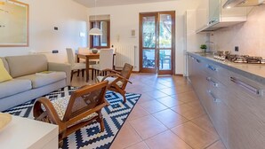 A modern kitchen with a gas stove, wooden cabinets, and a dining area with a table and chairs. - Alessandra 2 Apartment by Wonderful Italy (Padenghe sul Garda)