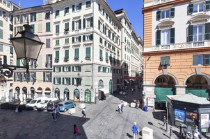 Una plaza histórica con pavimento de adoquines, arquitectura europea clásica y un espacio abierto central.