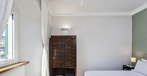 A bedroom with a bed, a nightstand, a dresser, and a window with curtains. - San Lorenzo View Apartment 5 by Wonderful Italy (Genoa)