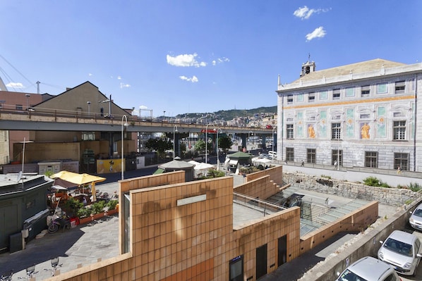 A rooftop terrace with a view of a cityscape, a covered outdoor seating area, and a building with classical architecture.