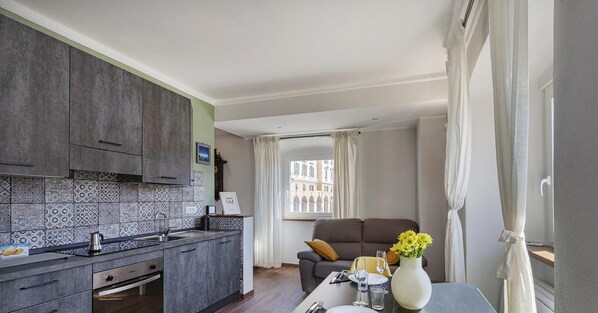 A modern kitchen with dark cabinets, patterned backsplash, and a dining area with a table set for two.