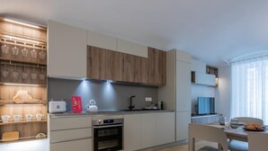 A modern kitchen with wooden cabinets, a built-in oven, and a dining area with a table and chairs.