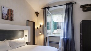 A hotel room with a bed, a window with curtains, a wall-mounted picture, and a wardrobe.