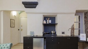 A compact kitchen with a built-in dishwasher, a small countertop, and a brick wall.