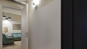 A room with a white door, a light blue sofa, a lamp, and a framed picture on the wall.