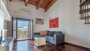 A living room with a wooden floor, a gray sofa, a white side table, and a painting on the wall.