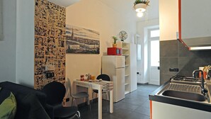 A compact living space with a kitchenette, a dining area, and a wall decorated with a collage of images.