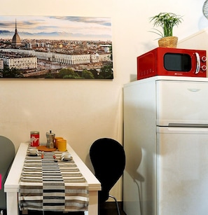 Compact living space with a kitchenette, featuring a refrigerator, microwave, and coffee maker.