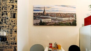 A room with a cityscape painting, a red microwave, and a table with various items.