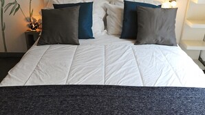 A neatly made bed with white bedding and two dark gray pillows.