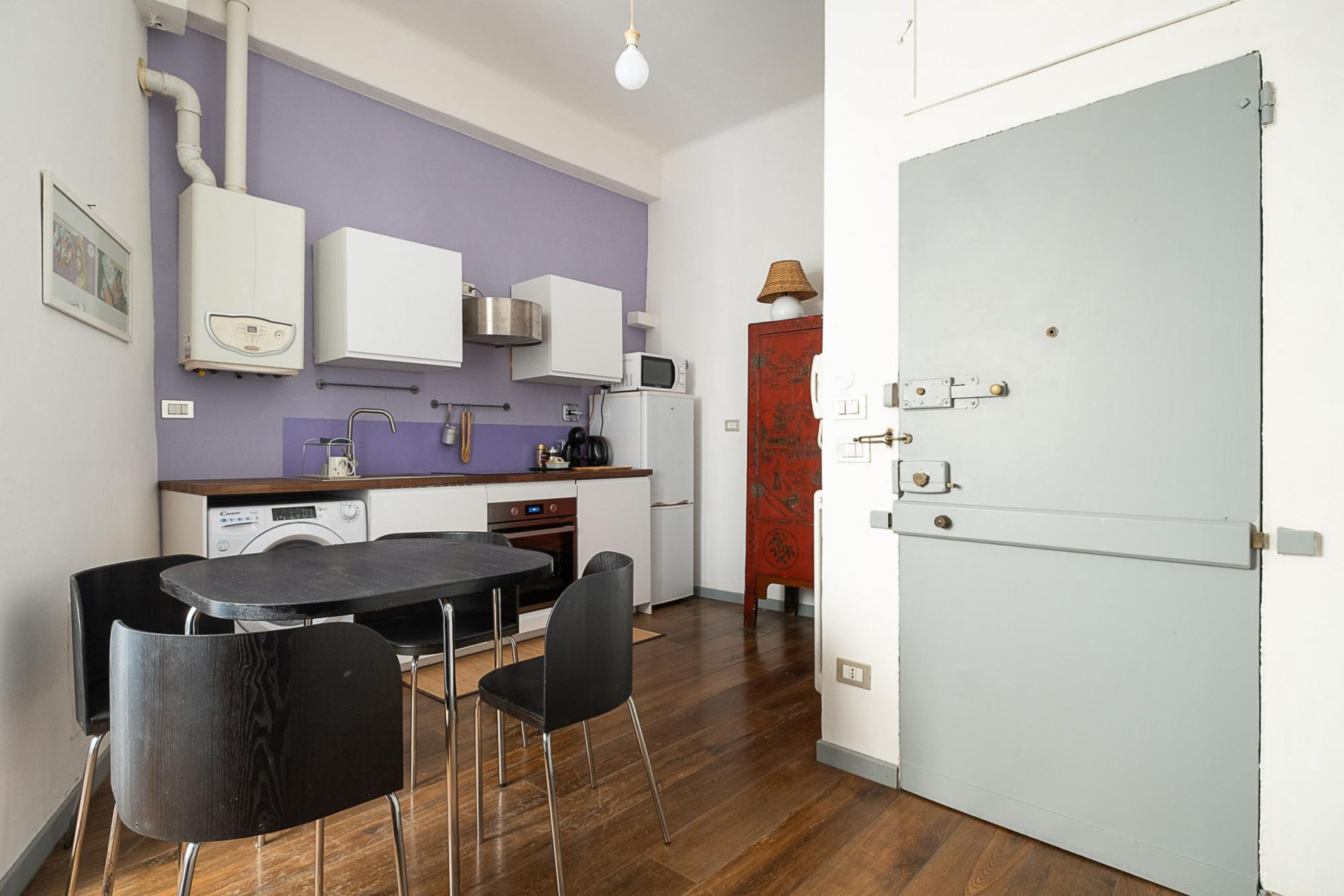 A compact kitchen with a dining area, a washing machine, a microwave, and a refrigerator.