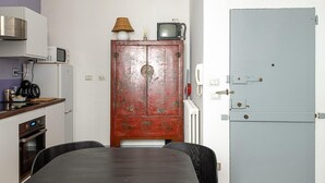 A compact kitchen with a dining table, chairs, a microwave, a stove, and a refrigerator.