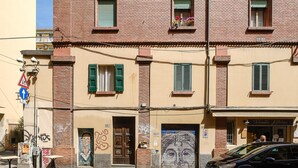 A building with a brick facade, green shutters, and a mural on the lower wall.