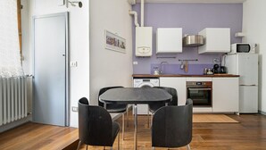 A compact kitchen with a dining area, featuring a washing machine, oven, and a microwave.